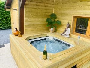 a hot tub in a wooden house with a bottle of wine at Chalet La Bohème in Prouilly