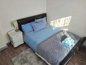 a bedroom with a bed with blue sheets and a night stand at Bellas place in Yambol