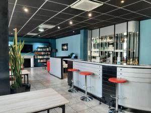 a bar in a restaurant with red stools at Brit Hotel Mulhouse Centre in Mulhouse
