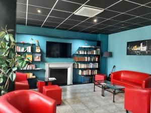 a waiting room with red chairs and a fireplace at Brit Hotel Mulhouse Centre in Mulhouse