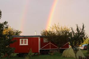 a rainbow over a red trailer and a tent at Ferienhof Löbejün in Löbejün