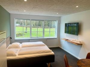 a bedroom with two beds and a large window at Blommenslyst Kro in Blommenslyst