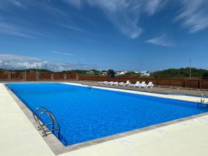 a large swimming pool with chairs and blue water at Burrowhead Holiday Village in Isle of Whithorn