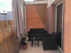 a balcony with a chair and a couch and an umbrella at Studio loft city center in Tarnos