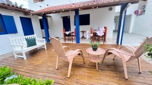 a patio with wicker chairs and a table on a wooden deck at Casa da Praia Pousada in Torres