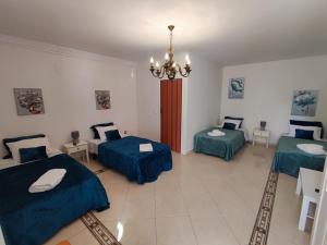 a room with three beds and a chandelier at Alenquer, Alojamento Santa Catarina in Alenquer