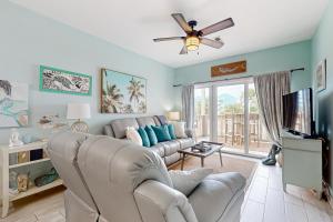 a living room with a couch and a tv at Condo with partial bay view onsite fishing dock beach access & shared pool in Pensacola Beach