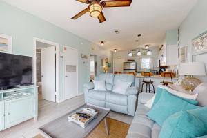 a living room with a couch and a ceiling fan at Condo with partial bay view onsite fishing dock beach access & shared pool in Pensacola Beach