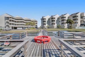 a red table on a deck in front of some apartment buildings at Condo with partial bay view onsite fishing dock beach access & shared pool in Pensacola Beach
