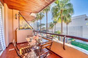 a balcony with a table and chairs and palm trees at Ideal Property Mallorca - Bella Italia in Alcudia
