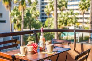 a wooden table with a bottle and cups on a balcony at Ideal Property Mallorca - Bella Italia in Alcudia