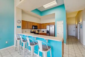 a kitchen with blue walls and bar stools at Beachfront Condo with amazing views shared pool and beach access in Navarre +15 photos
