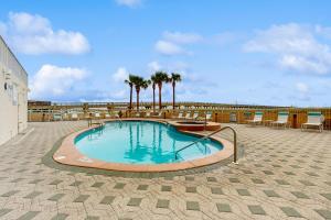a large swimming pool with chairs and palm trees at Beachfront Condo with amazing views shared pool and beach access in Navarre