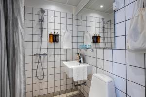 a white tiled bathroom with a sink and a shower at Hotel Atlantic in Aarhus +40 photos