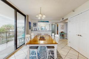 a dining room with a table and chairs and a balcony at Beachfront condo shared pool large balcony and beach access in Navarre