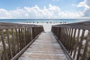 a wooden boardwalk to the beach with people on the beach at Beachfront condo shared pool large balcony and beach access in Navarre