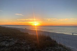 a sunset on a beach with the sun setting at Beachfront condo shared pool large balcony and beach access in Navarre