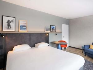 a bedroom with a white bed and a blue chair at ibis Styles Den Haag Scheveningen in Scheveningen +102 photos