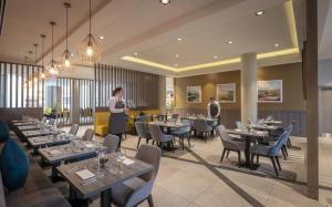 a restaurant with tables and chairs and two people in the background at Maldron Hotel Glasgow City in Glasgow