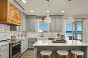 a kitchen with white cabinets and a large island with bar stools at Stunning beachfront condo with shared pool & beach access in Santa Rosa Beach +25 photos
