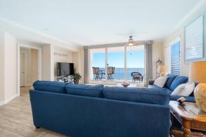 a living room with a blue couch and a view of the ocean at Gorgeous cozy beachfront condo with pool pool spa & beach access in Perdido Key