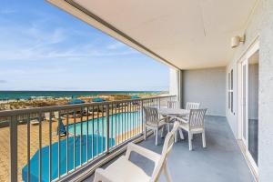 a balcony with a table and chairs and a pool at Beautiful beachfront condo with shared pool & beach access in Fort Walton Beach