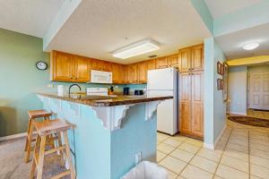 a kitchen with wooden cabinets and a white refrigerator at Beautiful beachfront condo with shared pool & beach access in Fort Walton Beach +28 photos