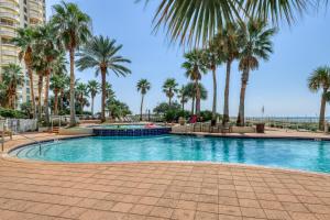 a swimming pool with palm trees in a resort at Gorgeous cozy beachfront condo with pool pool spa & beach access in Perdido Key