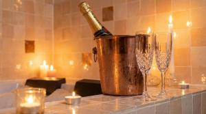 a bottle of champagne in a bucket next to two wine glasses at Suite Marrakech avec jacuzzi privatif Love Room romantique proche Toulouse in Auterive