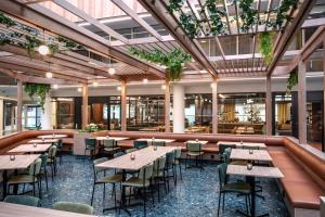 a restaurant with wooden tables and chairs and plants at Thon Hotel Vika Atrium in Oslo