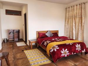 a bedroom with a bed with red and yellow bedspread at Mangat Farm, Kanatal in Kanatal +12 photos