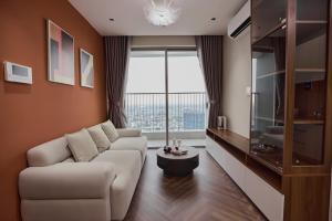 a living room with a white couch and a large window at HongHome Happy One Central in Ga Phú Văn