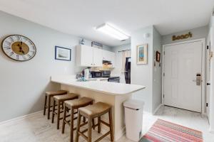 a kitchen with a counter with stools and a clock on the wall at Beautiful coastal studio condo with pool in Santa Rosa Beach +21 photos