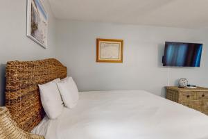 a bedroom with a white bed with a woven headboard at Beautiful coastal studio condo with pool in Santa Rosa Beach