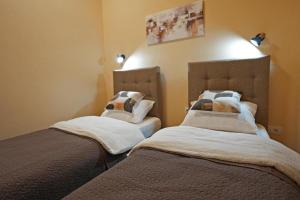 a bedroom with two beds with white sheets at Apartmani u srcu grada in Zrenjanin