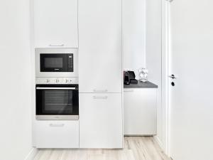 a white kitchen with white cabinets and a microwave at Milano Suite Francine in Milan