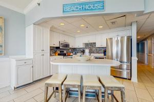 a kitchen with a counter with stools and a refrigerator at Conveniently located Gulf condo with spacious layout pool & pickleball in Seacrest