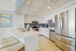 a kitchen with white cabinets and a refrigerator at Conveniently located Gulf condo with spacious layout pool & pickleball in Seacrest +37 photos
