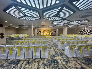 a banquet hall with white and yellow tables and chairs at Pam Premium Hotel Vadodara in Vadodara