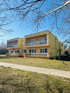 a large yellow building on a grass field at Thermal Next I Weninger Apartman Kiskunhalas in Kiskunhalas
