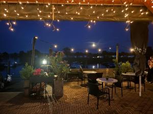 a patio with tables and chairs at night with lights at Bell Tent aan de haven in Heerewaarden