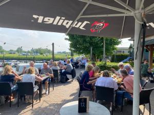 a group of people sitting at tables under an umbrella at Bell Tent aan de haven in Heerewaarden
