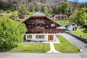 a large wooden house on a hill with trees at La Ferme de Sous-Lachat in Samoëns