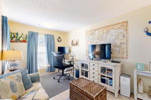 a living room with a couch and a tv at Spacious Condo with Balcony in Navarre Beach with Shared Pool in Navarre