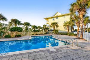 a swimming pool in front of a building with palm trees at Spacious Condo with Balcony in Navarre Beach with Shared Pool in Navarre