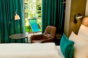a room with a bed and a chair and a window at Motel One München-Messe in Munich