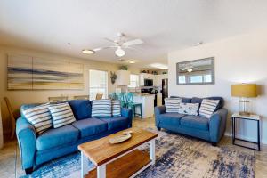 a living room with two blue couches and a table at Bright condo with shared pool beach access & central location in Navarre