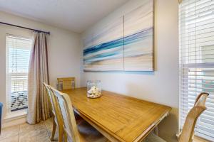 a dining room with a wooden table and chairs at Bright condo with shared pool beach access & central location in Navarre