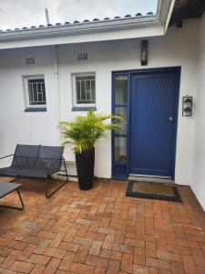 a blue door of a house with a chair and a plant at Ocean Sands Accommodation in Richards Bay