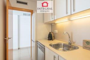 a kitchen with white cabinets and a sink at Paradís Platja Apartment in Palamós